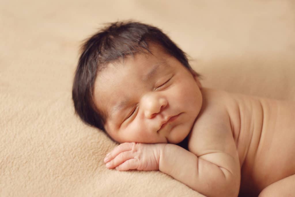 precious photo of newborn baby laying on tan blanket sleeping