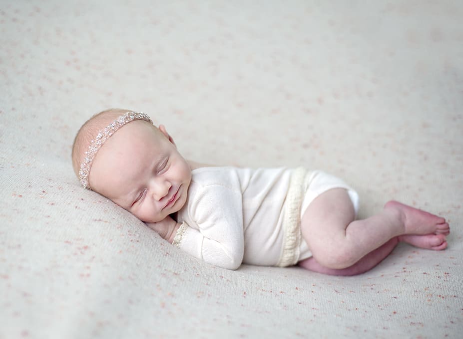 Baby dressed in white sleeping on a blanket during a session with a newborn photographer in Frederick MD