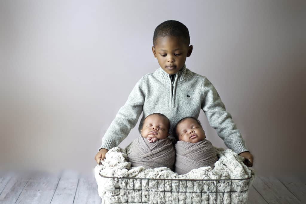 photo of baltimore newborn twins with big brother watching over them in a basket 