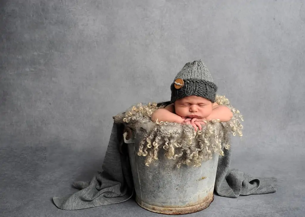 image a newborn baby in a bucket on a gray background 