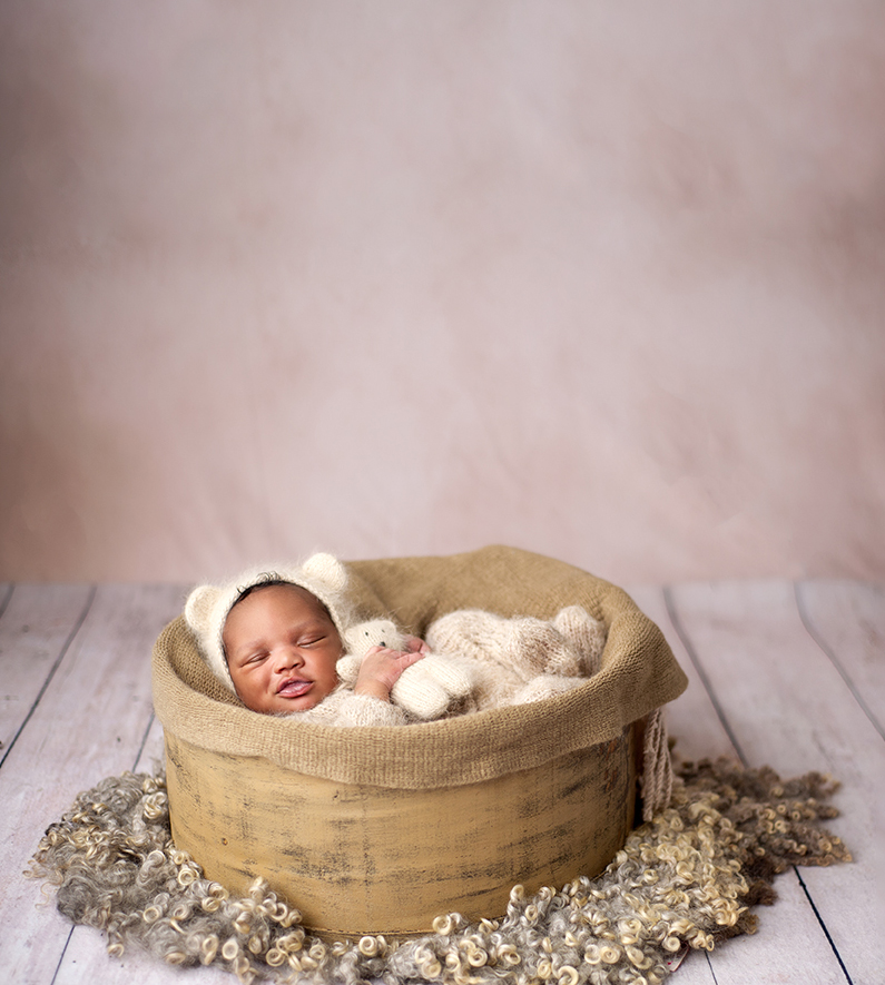 newborn photos in maryland of a little boy dressed in a bear outfit holding a little matching bear