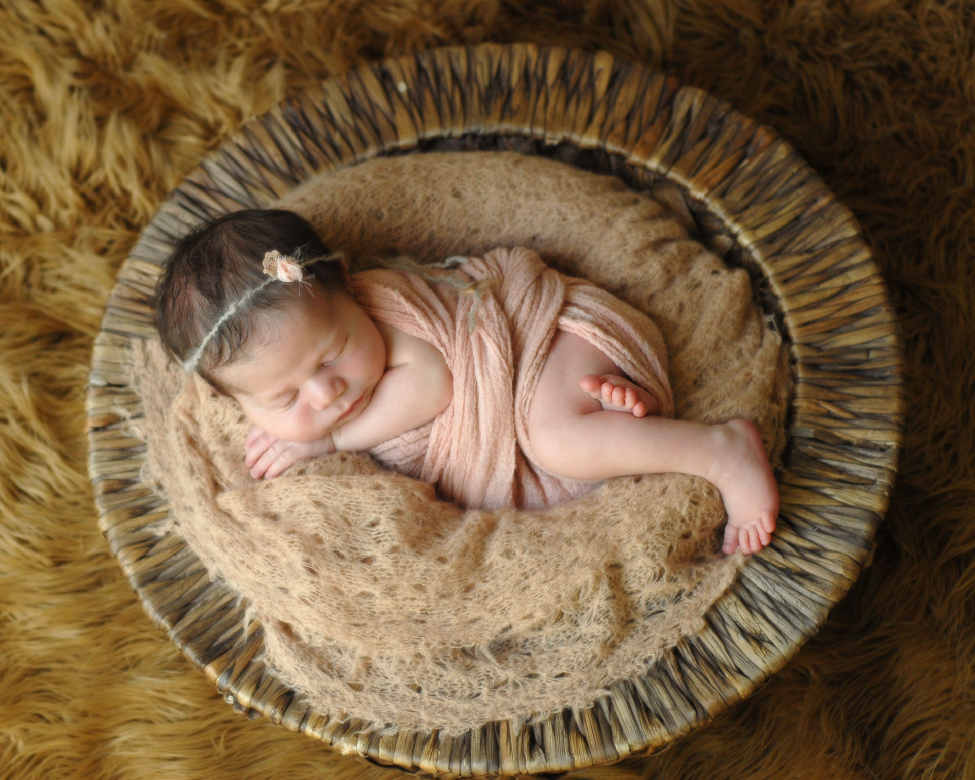 newborn photo of a little girl curled up sleeping wrapped pink