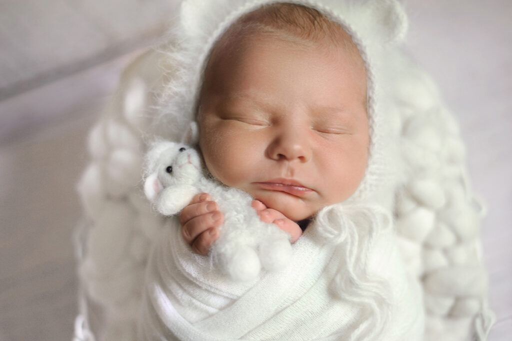 Baltimore Newborn Photography image of baby girl wrapped in all white holding a baby lanb